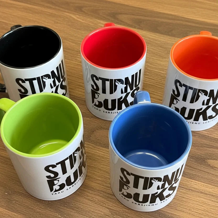 Five colorful mugs with 'STIRNU BUKS' text on a textured surface