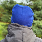 Person wearing a blue beanie and gray jacket in a forest setting