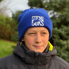 Person wearing a blue beanie with text and a dark jacket outdoors