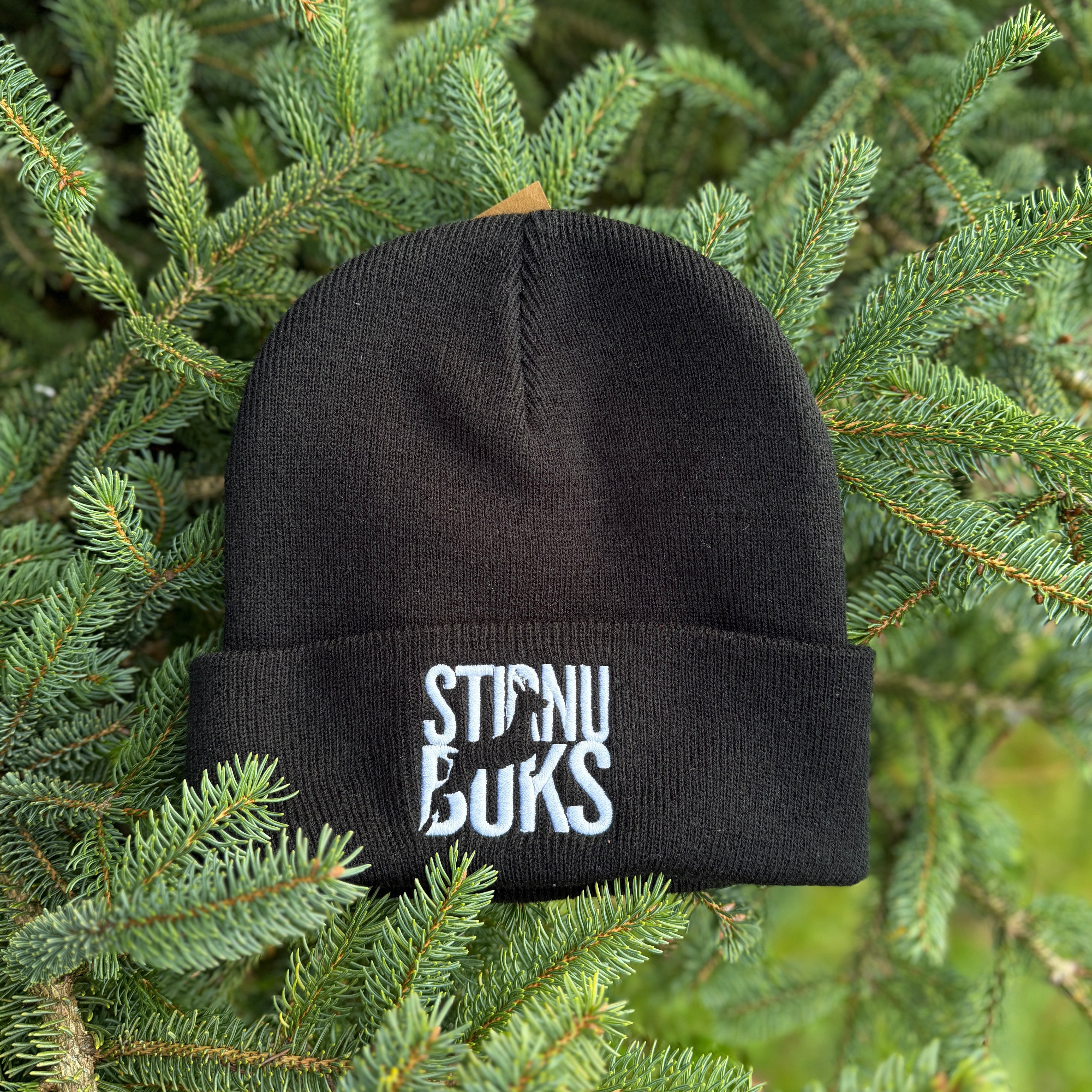 Black beanie with 'STIRNU BUKS' text on a green pine branch background